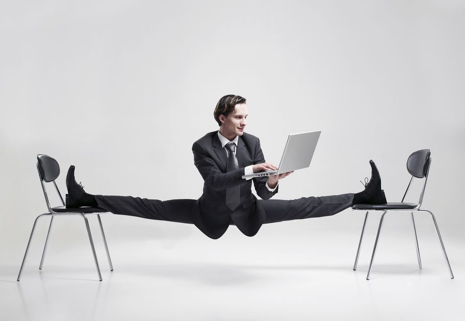 businessman-balancing-to-two-chairs-holding-laptop-84120653-5727f0b25f9b589e340ed5a3.jpg